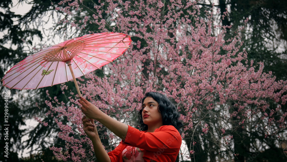 Model posing with pink parasol in front of blooming cherry trees