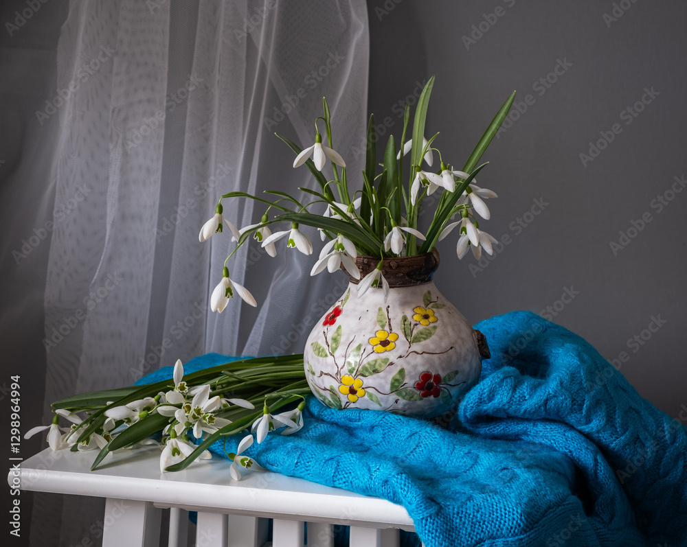 An Elegant Floral Arrangement Placed in a Ceramic Pitcher Surrounded by Beautiful Textiles
