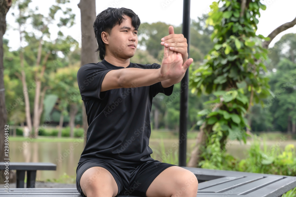 Young Asian male sportsman warm up before doing exercise in green nature park