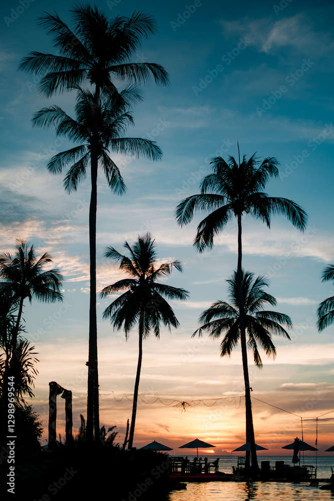 A tropical beach at a stunning sunset with silhouettes of palm trees reflected in the water. A tropical beach at a stunning sunset with silhouettes of palm trees reflected in the water.