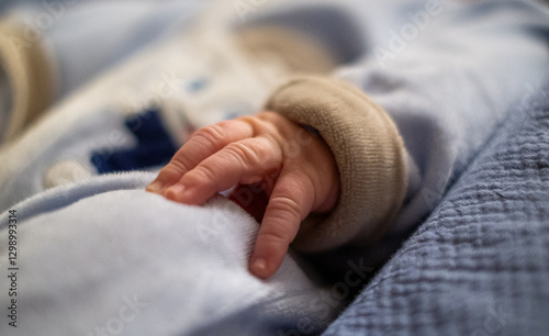 Newborn holding parent's finger with hand