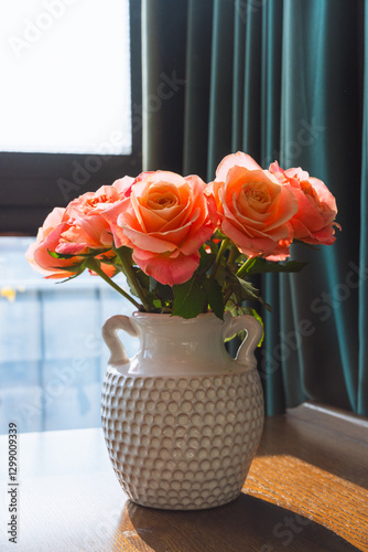 Fotografía A beautiful bouquet of pink rose flowers in the vase on the wooden table under the sunlight