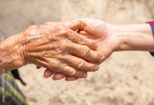 Hand einer alten Frau in der Hand einer jungen Frau