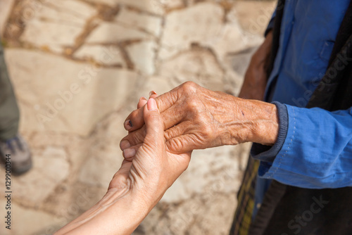 Hand einer alten Frau in der Hand einer jungen Frau