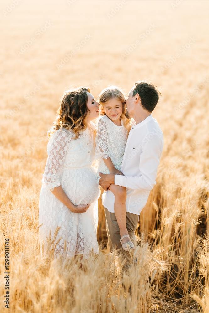 A happy family is waiting for a child, a pregnant woman, a man and their daughter in a wheat field A happy family is waiting for a child, a pregnant woman, a man and their daughter in a wheat field