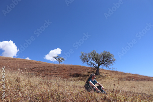 Wallpaper Mural Man sitting on a dry hillside under a clear blue sky in Coyllurqui, Perú. Hispanic man sits on a dry grassy hillside Torontodigital.ca