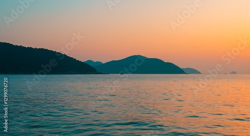 Calm Beach at Sunset with Silhouetted Hills and Colorful Sky Reflection