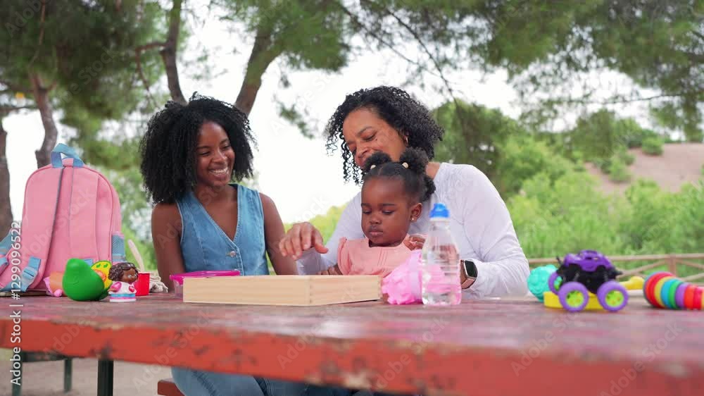 Multigenerational african american family sharing playful moments together, enjoying leisure time at park table with toys, smiling and connecting