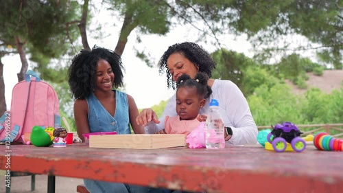 Multigenerational african american family sharing playful moments together, enjoying leisure time at park table with toys, smiling and connecting