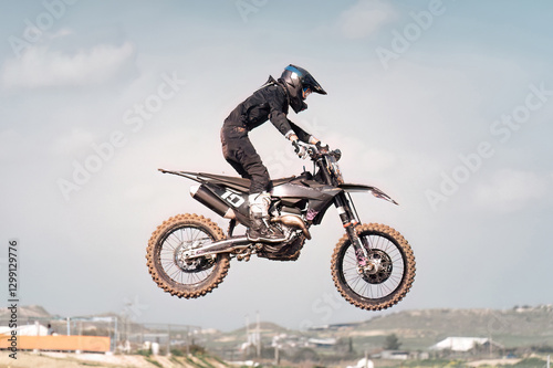 Professional motocross rider performing a jump during a race with blurred background