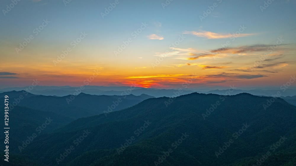 Aerial hyper lapse view of A breathtaking view of a colorful sunset over layered mountain silhouettes, with warm hues of orange, pink, and blue blending seamlessly across the sky. Aerial hyper lapse view of A breathtaking view of a colorful sunset over layered mountain silhouettes, with warm hues of orange, pink, and blue blending seamlessly across the sky.