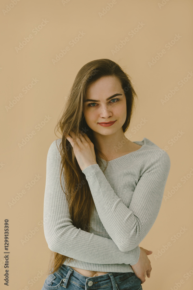 Obraz premium Portrait of Woman in Casual Grey Shirt Against Beige Background