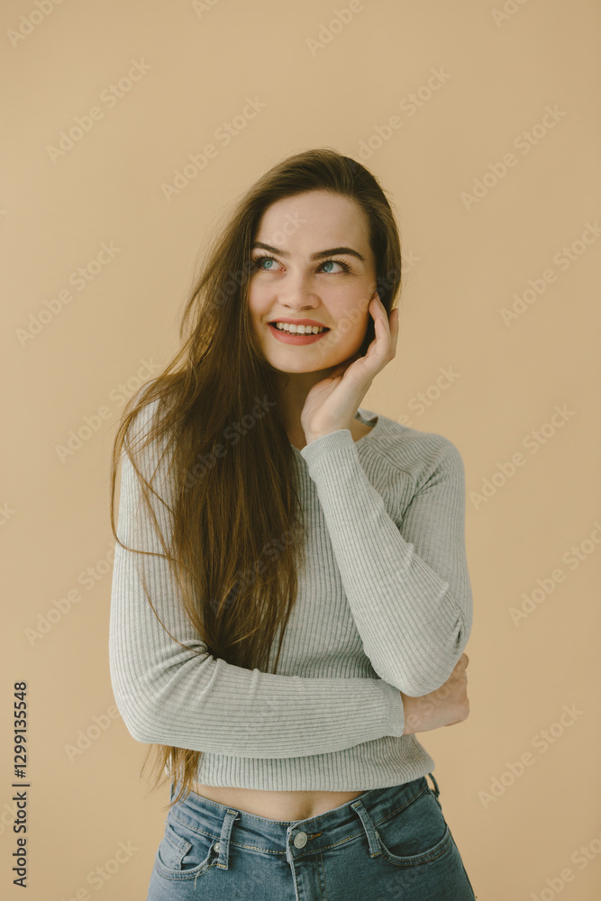 Smiling Woman Posing Against Beige Background in Casual Clothing Smiling Woman Posing Against Beige Background in Casual Clothing