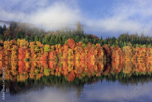 Picturesque Autumn Scene at Loch Faskally, Pitlochry, Perthshire, Scotland, Featuring Rich Fall Colors, Evergreen Forests, and a Stunning Water Reflection with Mist Rolling Over Distant Hills photo