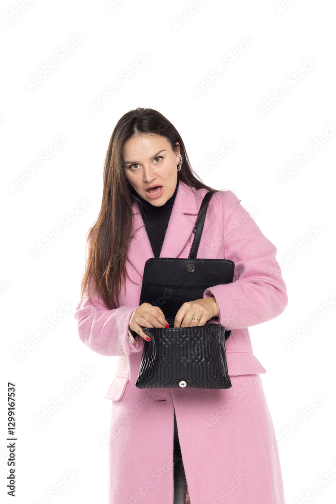 Naklejka premium Shocked woman looking at her empty purse on a white studio background.