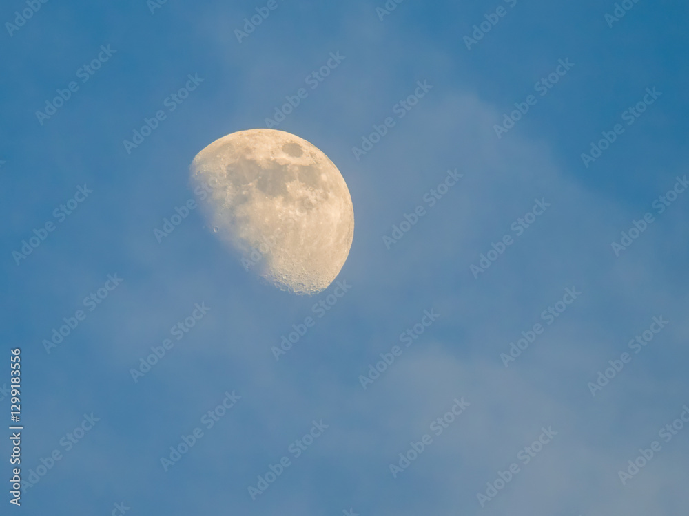 Sunlit yellow moon in blue sky in the daytime, white clouds Sunlit yellow moon in blue sky in the daytime, white clouds