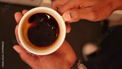 Professional barista carefully crafting latte art, swirling dark espresso in pristine white ceramic cup, revealing dynamic liquid motion and artisan coffee brewing technique