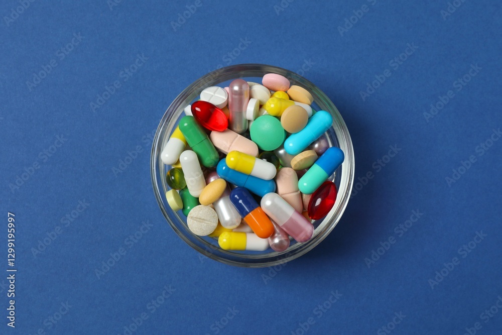 Bowl with pills on blue background, top view Bowl with pills on blue background, top view