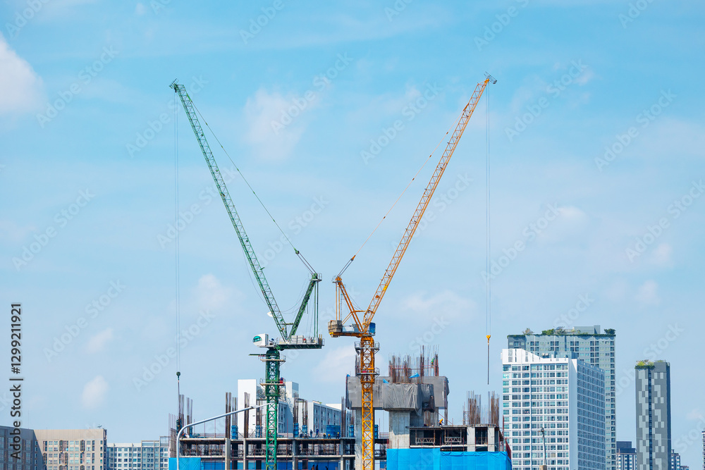 Construction cranes against Bangkok skyline under blue sky Construction cranes against Bangkok skyline under blue sky