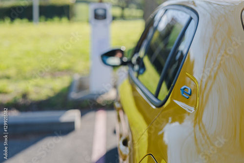 Yellow Electric Car Charging at Station in Greenery Setting
