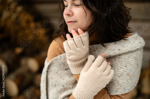 Girl enjoying a mindful moment in winter, wrapped in a warm scarf and fingerless gloves near a woodshed photo