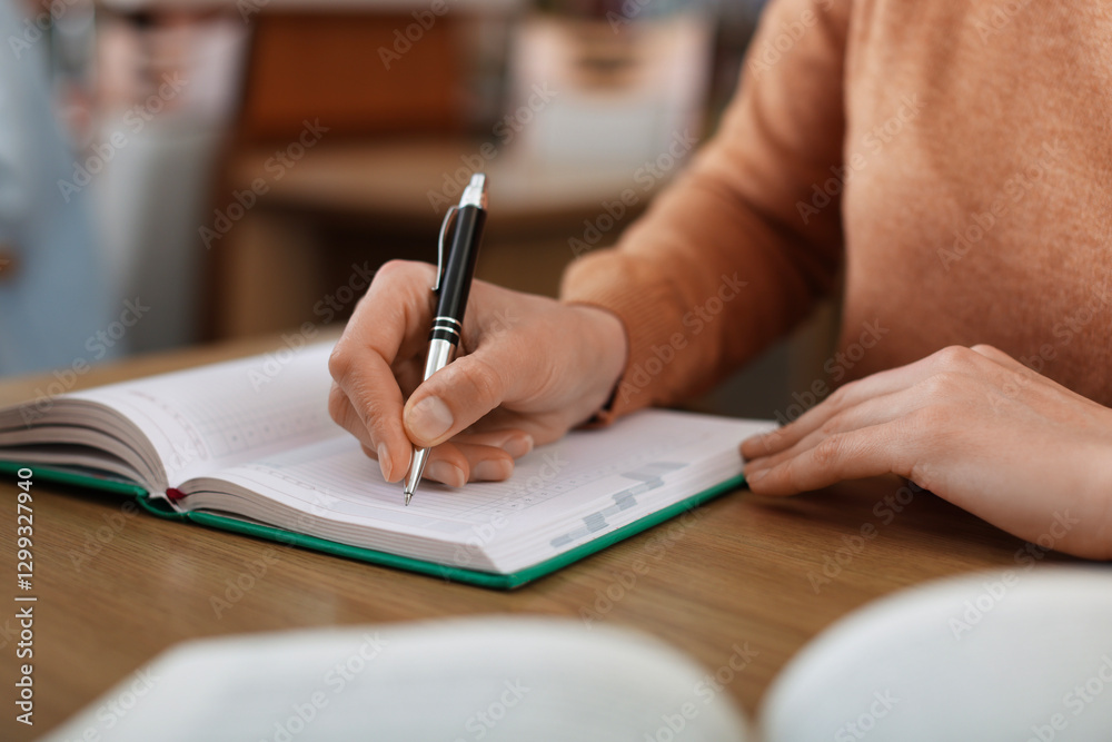 Woman taking notes at desk in library, closeup Woman taking notes at desk in library, closeup