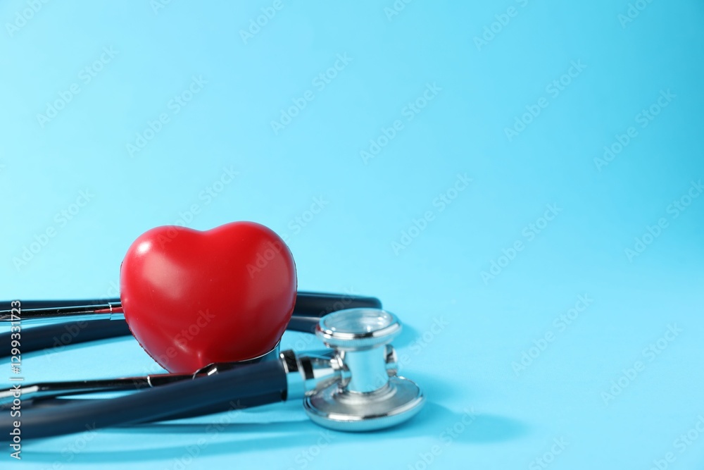 Stethoscope and red decorative heart on light background, closeup. Space for text Stethoscope and red decorative heart on light background, closeup. Space for text