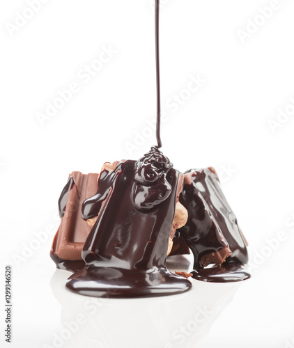 Rich chocolate sauce pouring over milk chocolate bar pieces photo