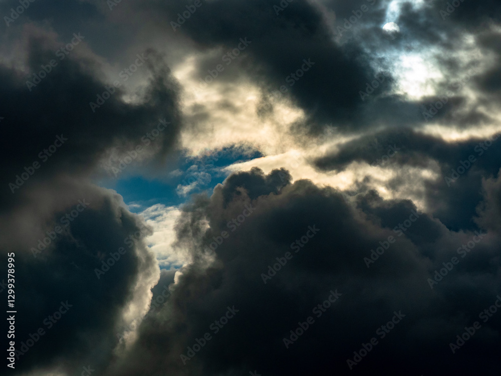 Fototapeta premium Sonne dringt durch den dunklen wolkenhimmel