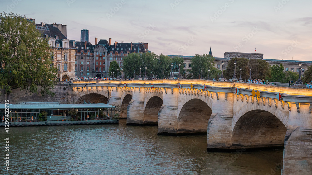 Lovely evening scene at the bridges over seine river in paris, with sun setting down in the distance. People and transport in direction of notre dame.