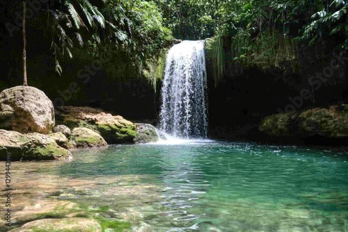 Serene waterfall cascading into a crystal-clear pool, surrounded by lush tropical greenery.