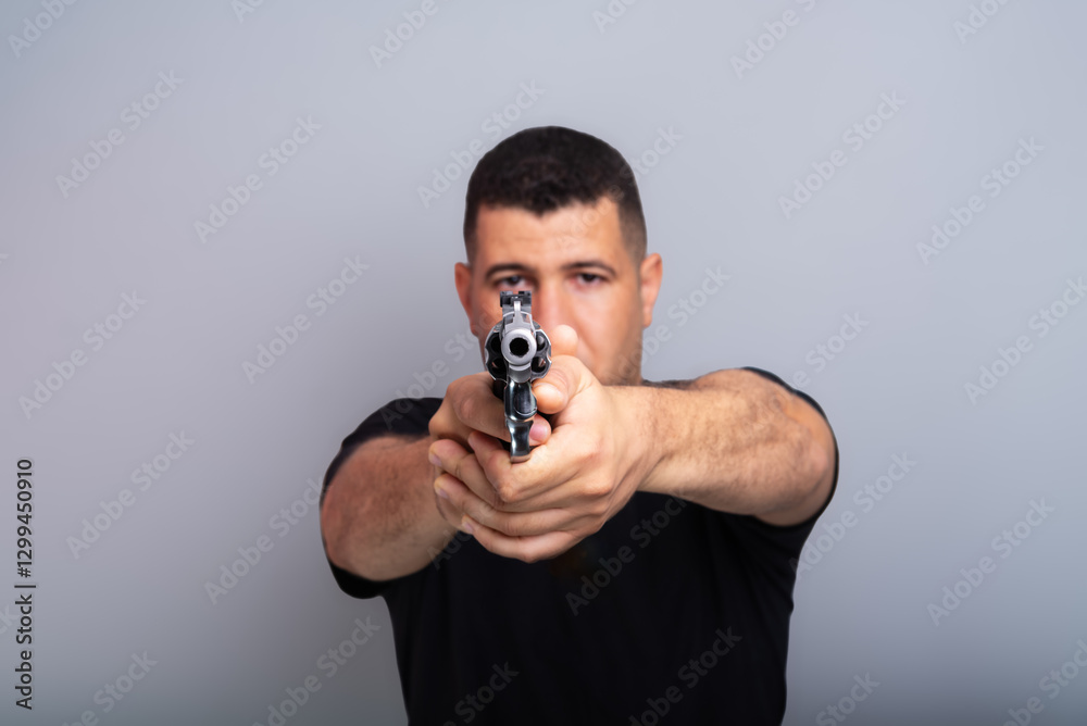 Studio portrait of a shooting instructor pointing a firearm at the camera. Studio portrait of a shooting instructor pointing a firearm at the camera.