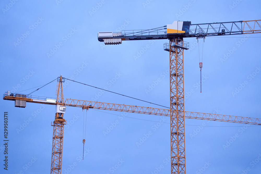 Construction cranes on the background of the sky at sunset. Construction of new residential complex. Construction cranes on the background of the sky at sunset. Construction of new residential complex.