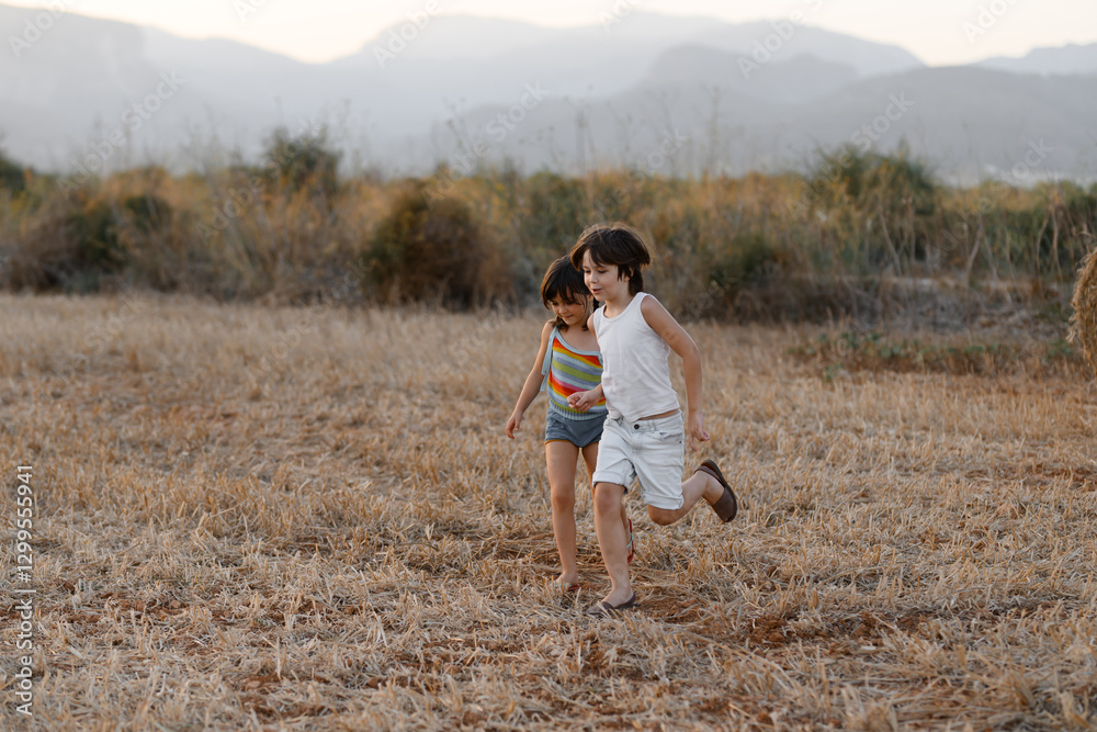 Two children running together in a scenic field Two children running together in a scenic field