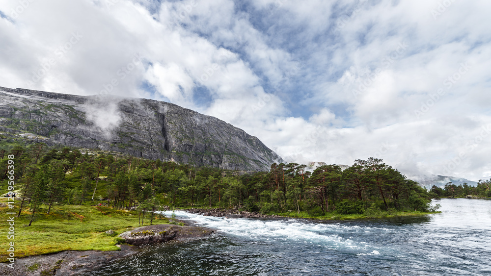 Obraz premium Breathtaking Natural Landscape: Majestic Mountains, Lush Forest, and Serene River Under a Cloudy Sky in Stunning Outdoor Adventure Scene