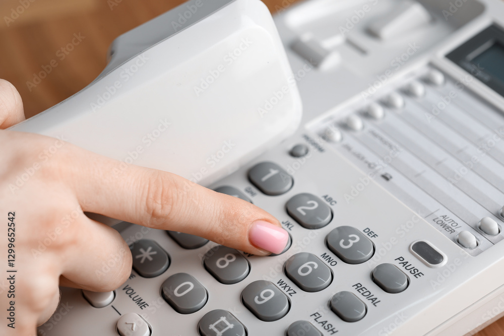Woman dialing number on telephone at table, closeup Woman dialing number on telephone at table, closeup