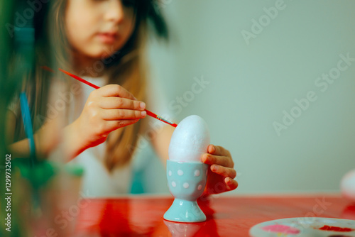 Child Painting an a polystyrene egg Egg at Home.  Funny little girl engaged in Easter artistic  activities 
 photo