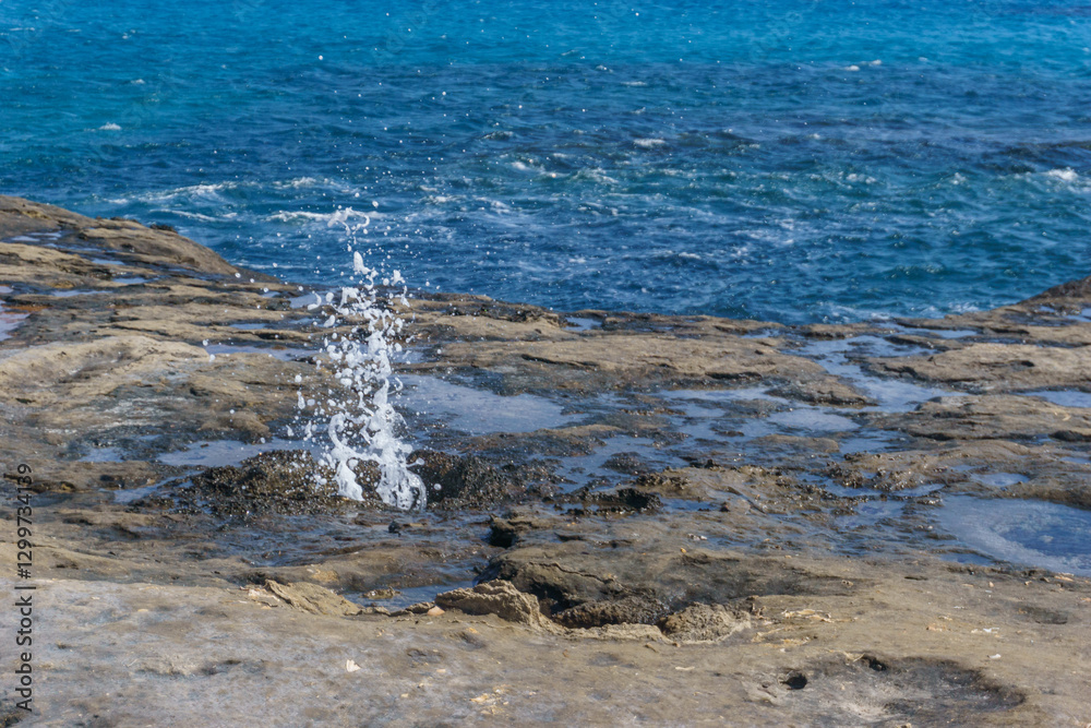 Fototapeta premium sea water splashing out of underground holes of petrified tree trunks and roots, Geopark Agios Nikolaos Petrified Forest, Laconia, Peloponnese, Greece