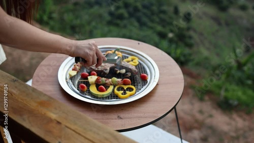 cooking outdoor as we camp on a mountain surrounded by abundant nature, family members are helping to cook both barbecue and grilled food, including meat and vegetables, close-up