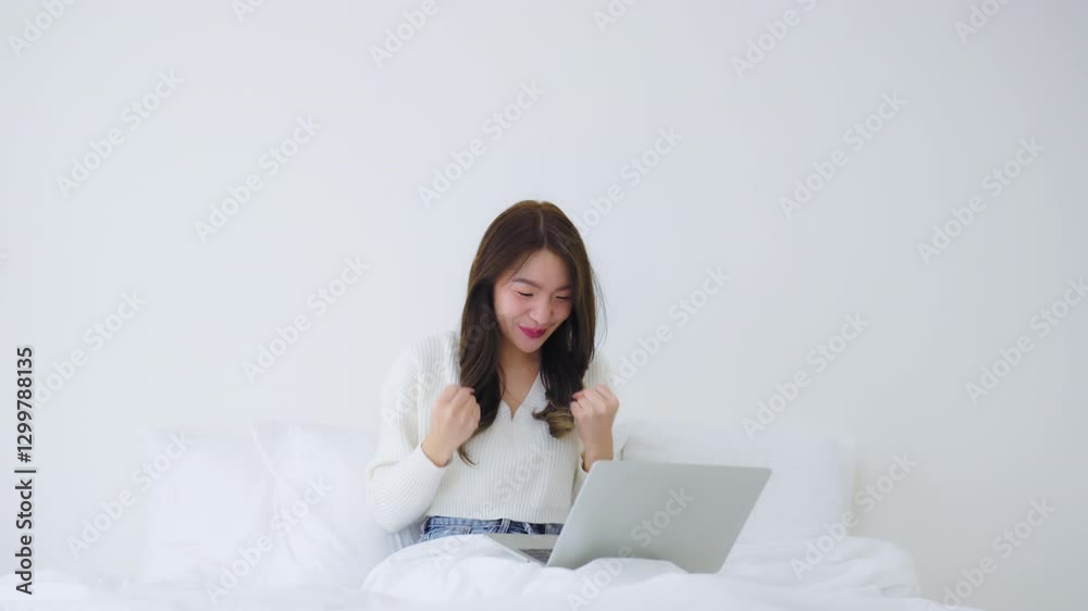 Happy young asian woman using computer laptop on bed in bedroom Happy young asian woman using computer laptop on bed in bedroom