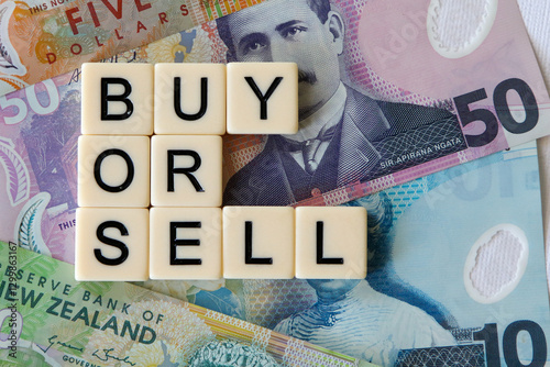 Buy or sell signage with a background of New Zealand notes.