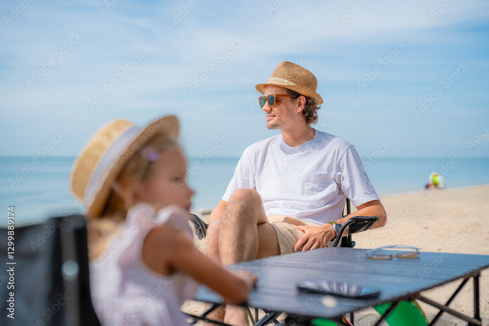 Fototapeta premium Father and daughter enjoy a relaxing day at the beach with sun hats and chairs