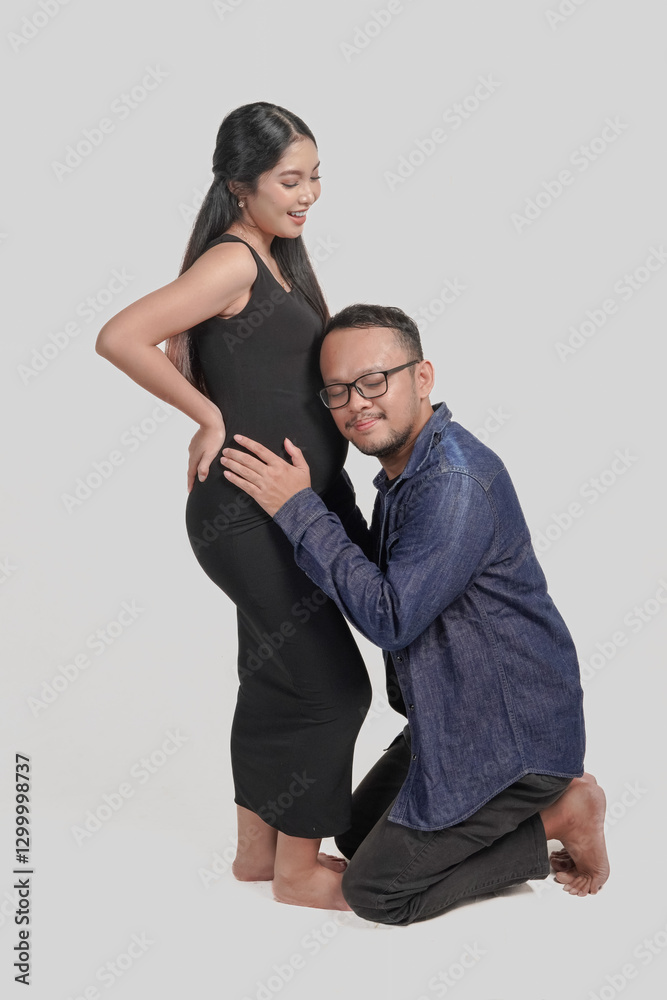 Excited husband leaning to his pregnant wife's belly stomach listening to the baby. Excited husband leaning to his pregnant wife's belly stomach listening to the baby.