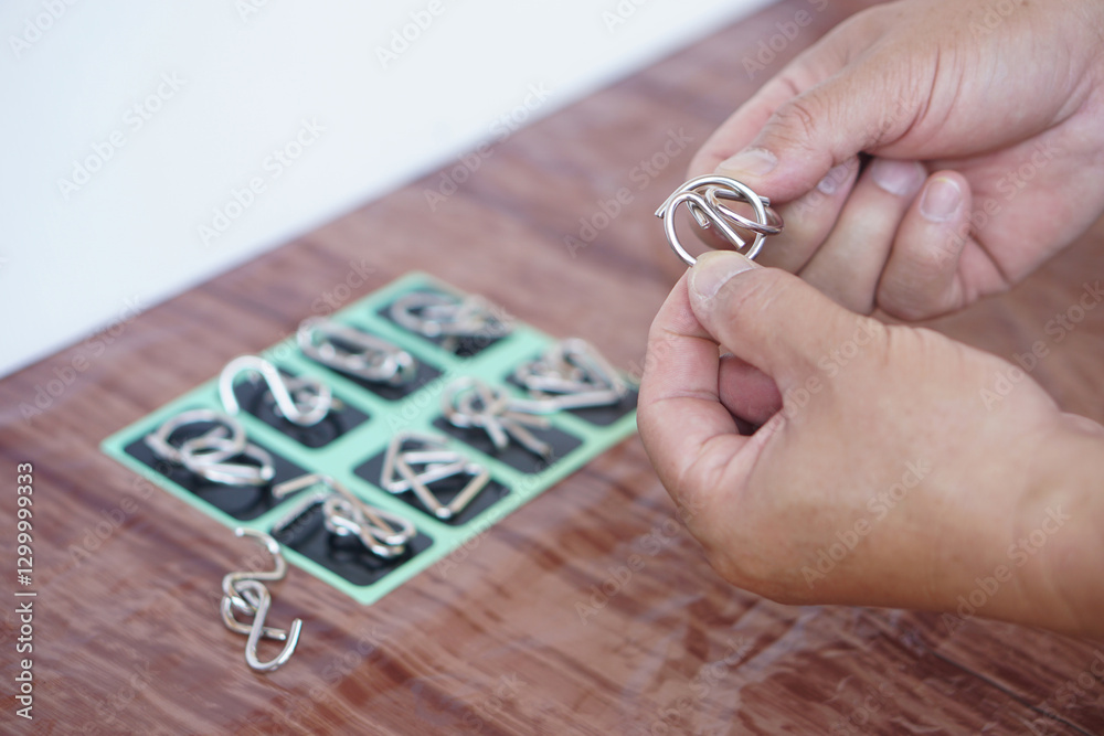 Fototapeta premium Close up hand hold small pieces of metal puzzles. Concept, creative toys or tools to practice critical thinking and concentration. Brain challenge. Mental and physical health therapy.
