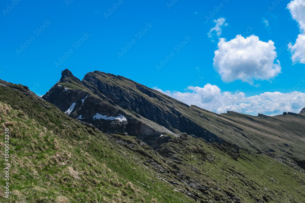 Fototapeta premium Jagged peaks ascend near mountain peak Reitereck, Austria. Steep, grassy slopes of the Ankogel Group in the Lieser-Maltatal region, Carinthia, creating a stunning alpine vista in remote Austrian Alps
