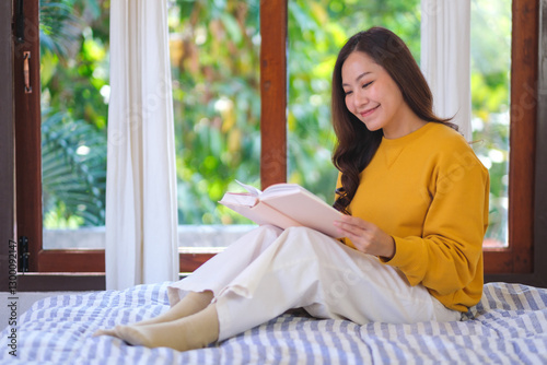 Wallpaper Mural Portrait image of a young woman reading a book on the bed at home Torontodigital.ca