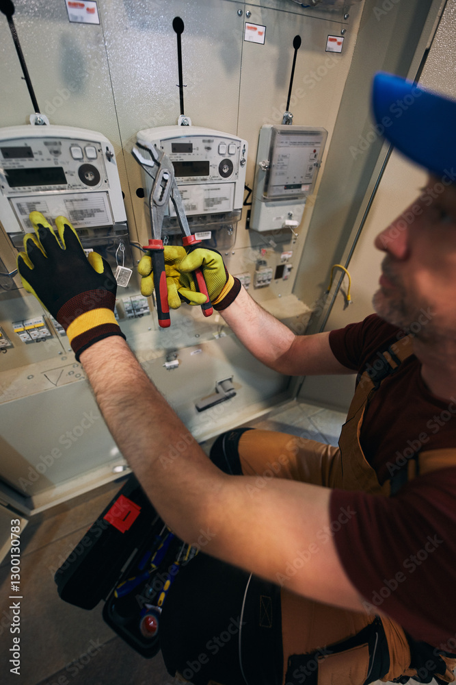 Electrician working on a modern electricity power meter station in a building.