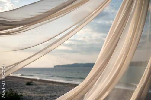 Sheer fabric curtains gently blowing in the breeze overlooking a serene beach landscape  