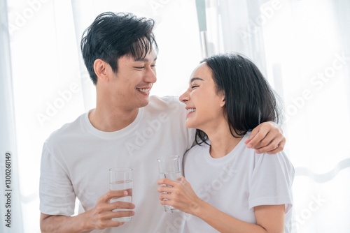 Young couple enjoys refreshing drinks and smiles together in bright indoor setting