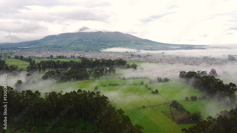 Aerial view of Machachi with fog covering fields and trees, highlighting the picturesque mountain backdrop Aerial view of Machachi with fog covering fields and trees, highlighting the picturesque mountain backdrop
